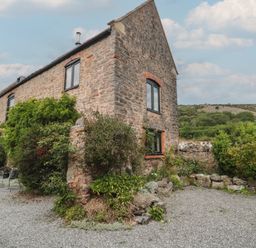 A stone building with windows and a seating area in a garden at The Barn in Compton Bishop near Cheddar