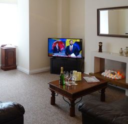 A living room with two leather sofas a wooden coffee table a fireplace and a television at 2 Carlton Mews in Exmouth