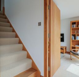 A hallway with stairs and a doorway leading to a sitting area at The Old Log Shed in Honiton