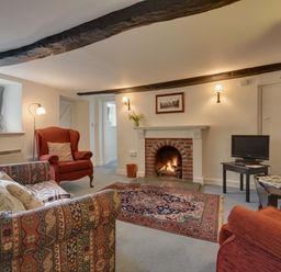 A living room with armchairs a fireplace a rug and a television at Lew Quarry Cottage Lewdown