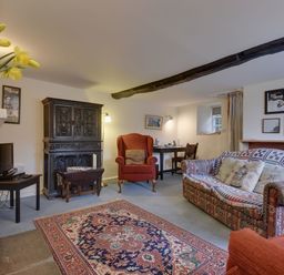 A living room with a patterned sofa armchair carpet and wooden furniture at Lew Quarry Cottage in Lewdown