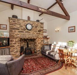 A living room with a fireplace and dining table at Miners Dry in Gulworthy, near Tavistock