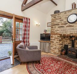 A living room with a fireplace and a chair at Miners Dry in Gulworthy, near Tavistock