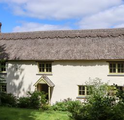 A cottage with a thatched roof and garden at Hope Cottage in Riddlecombe, near Winkleigh