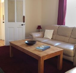 A living room with a wooden coffee table a leather sofa and a lamp at Hedgelea in North Tawton