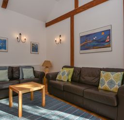 A living room with two brown leather sofas a wooden table a blue striped rug and wall art at Bradbridge Barn in Newton Ferrers