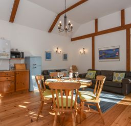 A kitchen and dining area with wooden chairs and table a blue refrigerator and brown sofas at Bradbridge Barn in Newton Ferrers