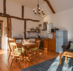 A kitchen and dining area with wooden table and chairs a blue fridge and a brown sofa at Bradbridge Barn in Newton Ferrers