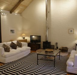 A living room with two white sofas and a striped rug at The Barn in Aveton Gifford