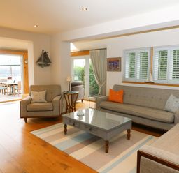 A living room with sofas a coffee table and a view of an outdoor dining area at Dove Cottage in Dittisham