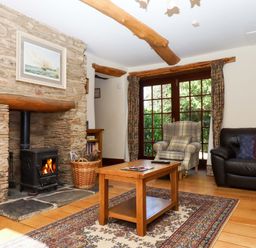 A living room with a fireplace and seating at Oak Tree in Halwell