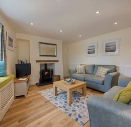 A living room with sofas a coffee table a fireplace and a window seat at Junket Cottage in Noss Mayo