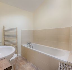 A bathroom with a bathtub sink toilet towel rack and wicker basket at Junket Cottage in Noss Mayo