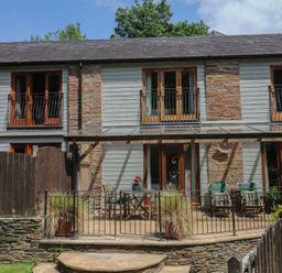 An outdoor area with a building, balcony, and patio at Fixit Cottage in Kingsbridge