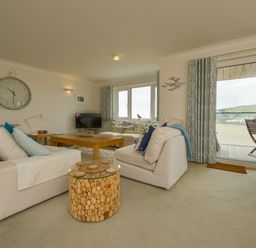 A living room with white sofas a wooden coffee table and a round cork side table with a glass top at 13 Burgh Island Causeway in Bigbury-on-Sea