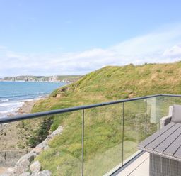 A balcony with a table and chairs overlooking the ocean at 27 Burgh Island Causeway Bigbury-on-Sea
