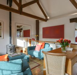 A living room with blue sofas and a wooden dining table with flowers at Mixit Cottage in Kingsbridge