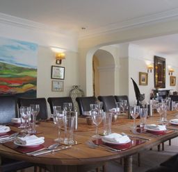 A dining room with a wooden table set with plates glasses and cutlery at Maristow Barton in Milton Combe near Lopwell Dam