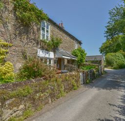 A stone cottage with plants and flowers along a narrow road at 1 Gabberwell Cottages in Kingston