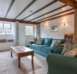 A living room with blue sofas a wooden coffee table and beams on the ceiling at 1 Gabberwell Cottages Kingston