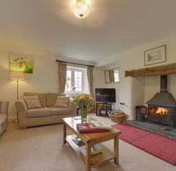 A living room with two sofas a wooden coffee table a fireplace and a television at Yellowland Farm in Holsworthy