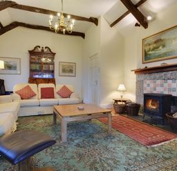 A living room with sofas coffee table fireplace and wooden beams at Higher Tumrose in Blisland