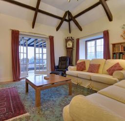 A living room with sofas pillows a wooden coffee table grandfather clock and a television at Higher Tumrose in Blisland