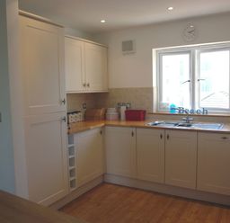 A kitchen with white cabinets wooden countertops a double sink and a window at The Loft in Bude
