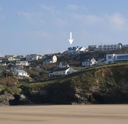 A coastal hillside with houses above a sandy beach at Seagulls Perch in Mawgan Porth