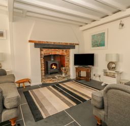 A living room with a fireplace a wood stove two sofas a television and a striped rug at Cousham Cottage in Kingsand And Cawsand