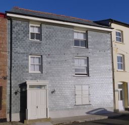 A row of houses with various window styles and a closed door at Nirvana in Kingsand And Cawsand