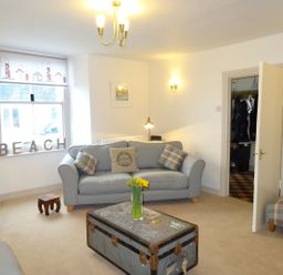 A living room with blue sofas a trunk coffee table and a window with beach letters at Nirvana Kingsand And Cawsand