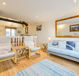A living room with two armchairs a sofa a large mirror on the wall and a striped rug on the floor at Chough Cottage in Kingsand And Cawsand
