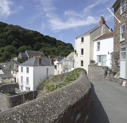A narrow street with stone walls and houses surrounded by trees at Balcony Cottage in Kingsand And Cawsand