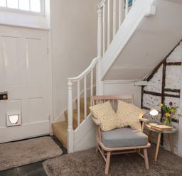 A hallway with a staircase and a chair at Tregonhawke Farmhouse in Millbrook