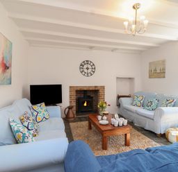 A living room with a sofa, table, and fireplace at Tregonhawke Farmhouse in Millbrook