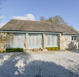 A single story stone cottage with large windows and gravel in front at Hideaway Barn in Charlestown