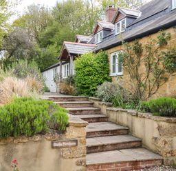 Stone steps leading to a stone and white farmhouse with plants along the pathway at Marles Farmhouse in Salwayash