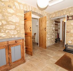 An entrance area with stone walls wooden doors a cabinet a shoe rack and a brown mat at Marles Farmhouse in Salwayash