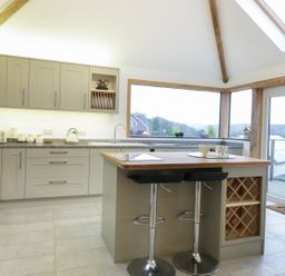 A kitchen with cabinets island and two bar stools at Treetops in Golant near Fowey