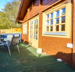An outdoor wooden deck with a table and chairs beside a wooden building with windows at St Hildas Lodge in Hinderwell near Runswick Bay