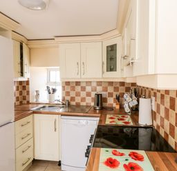 A kitchen with cream cabinets a white refrigerator a dishwasher a sink and a stove with poppy flower mats at Grange Farmhouse in Fethard-on-Sea County Wexford