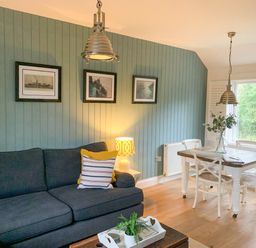 A living room with a dark sofa and dining table with white chairs at Oh Buoy in Charlestown
