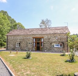 A stone house with a tiled roof and a gravel driveway surrounded by grass and small trees at Cilgwyn Bach in Llandysul