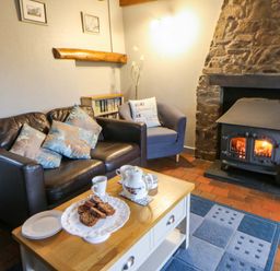 A living room with a fireplace and a coffee table at Old Farmhouse Cottage