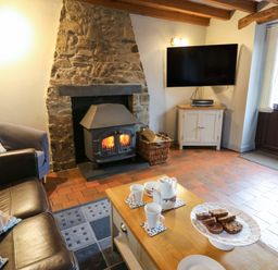 A living room with a fireplace and tea set at Old Farmhouse Cottage