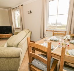 A living room with a dining table set and a television at 1 Park Nook Close in Waberthwaite
