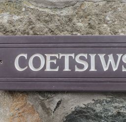 A sign reading Coetsiws mounted on a stone wall at Coetsiws in Clynnog Fawr