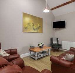 A living room with leather furniture and a television at Coetsiws in Clynnog Fawr