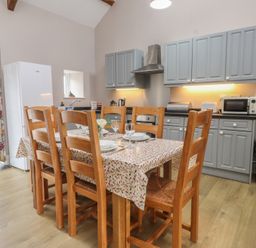 A kitchen with dining table and appliances at Coetsiws in Clynnog Fawr